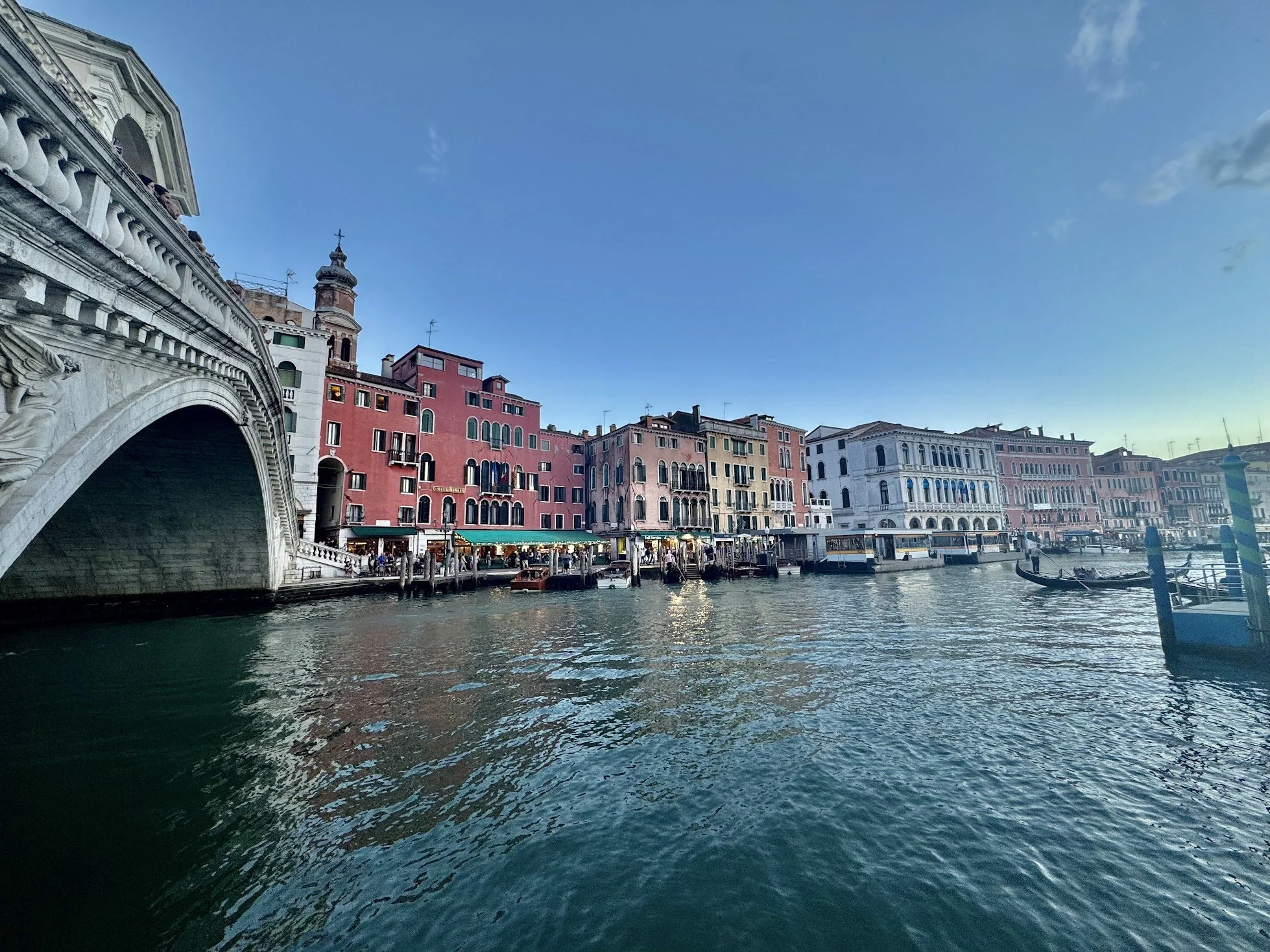 Colorful buildings along a canal in Venice, Italy with a stone bridge in the foreground and boats on the water.
