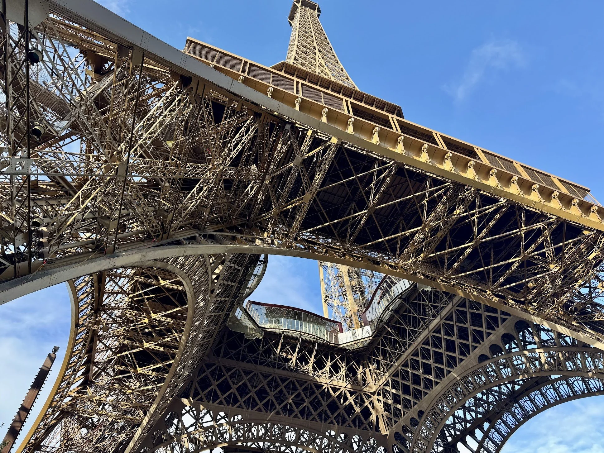 Close-up view of the Eiffel Tower's structural metal framework with a clear blue sky in the background.