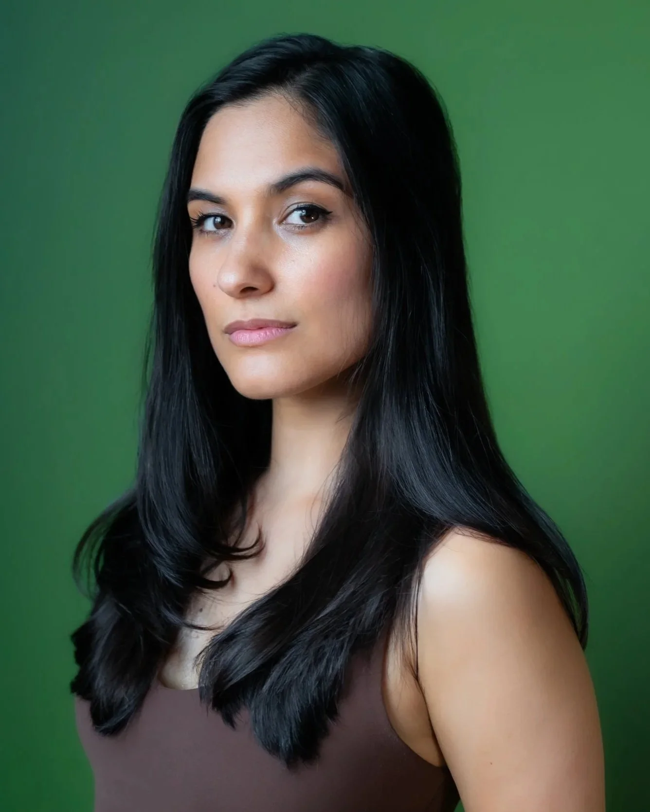 Headshot of Tara posing in front of a green backdrop