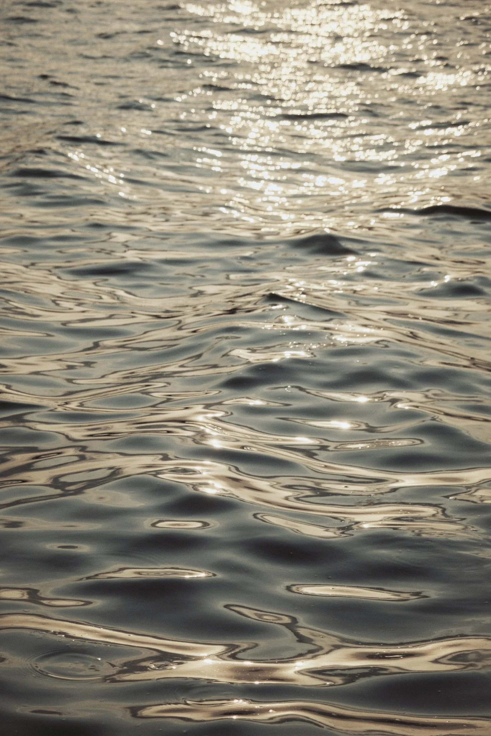 Shimmering water reflections on the surface of a body of water during sunset.