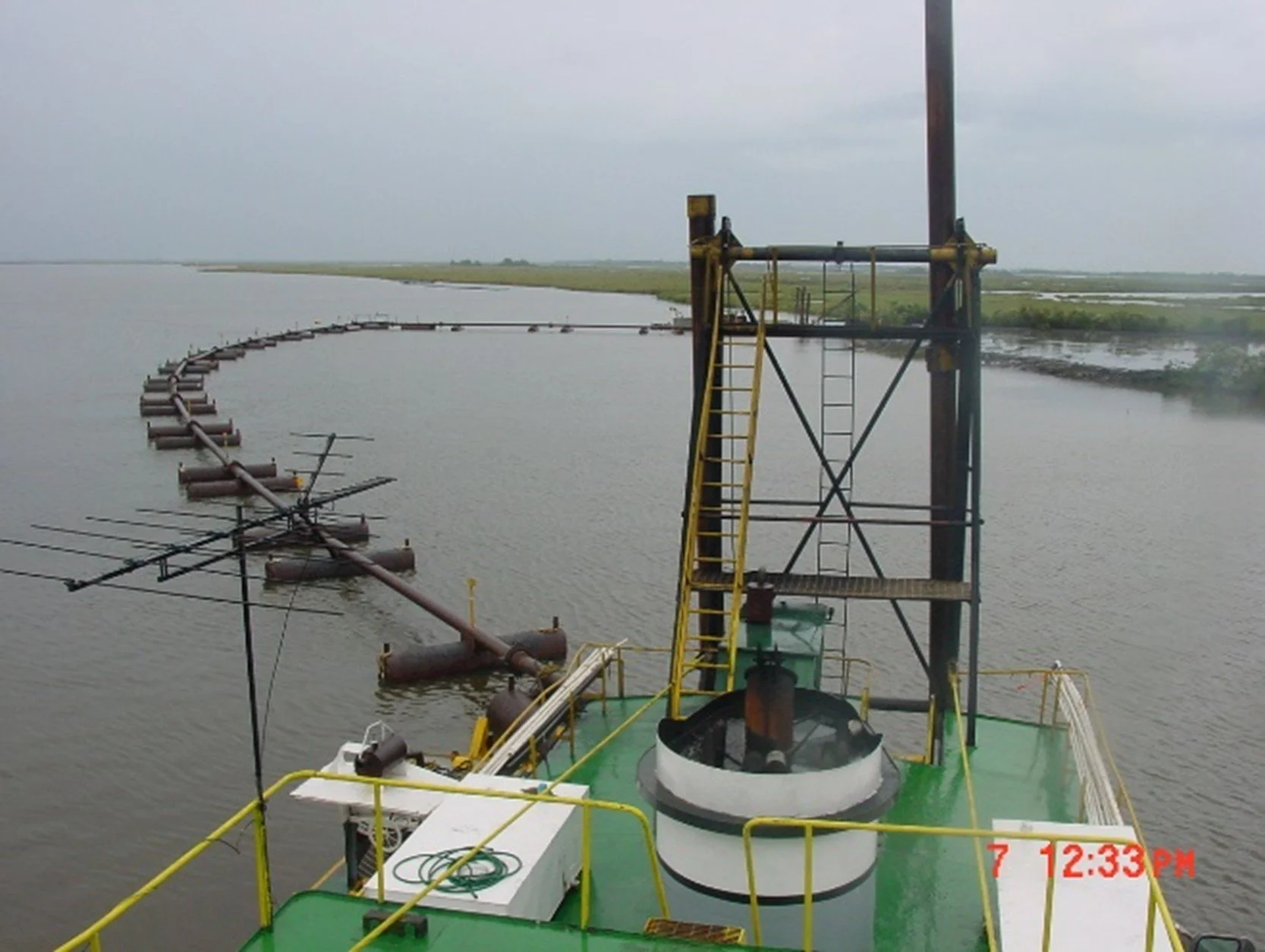 An image of a metal pipeline and watercraft with equipment on Bayou D'Inde