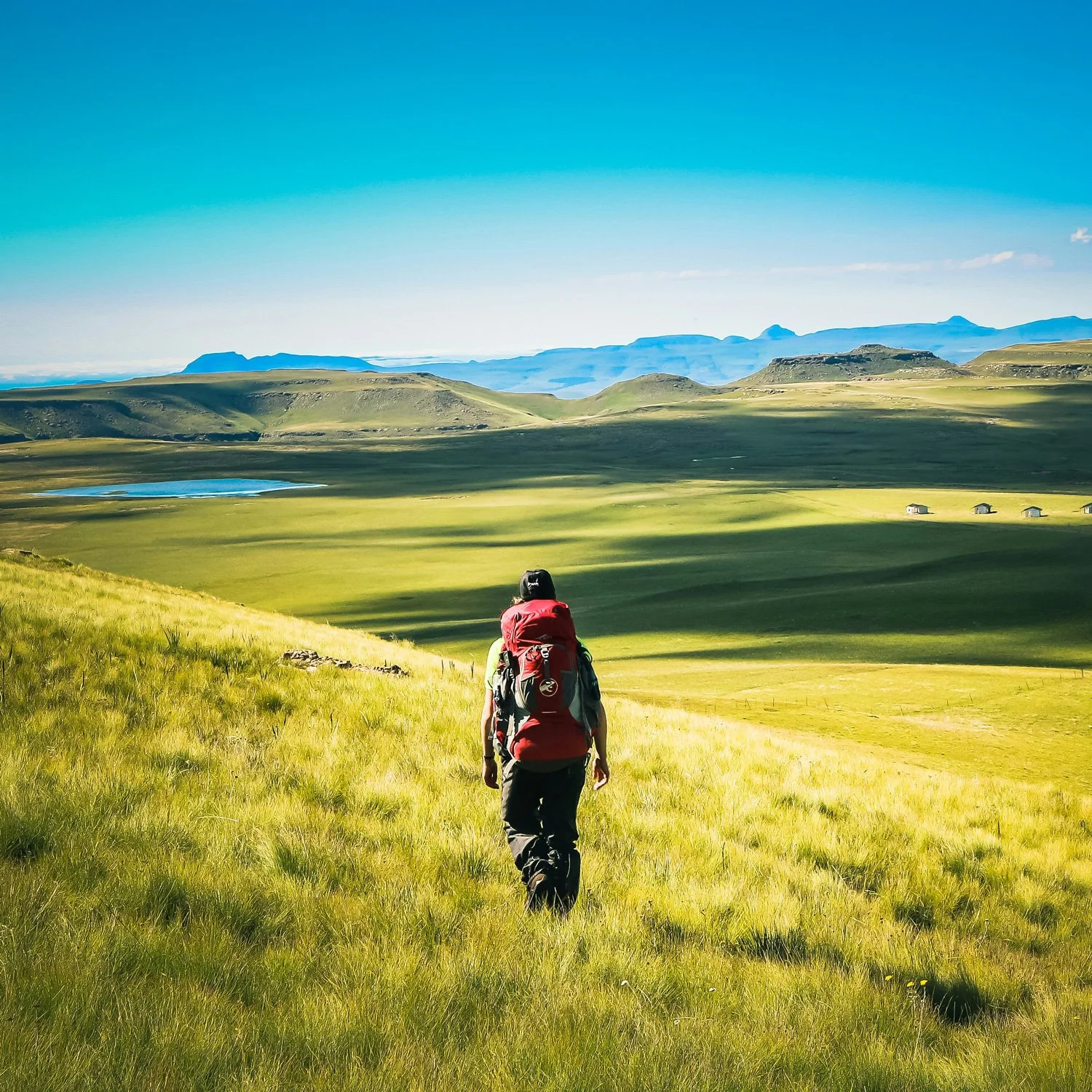 Backpacker walks through empty field.