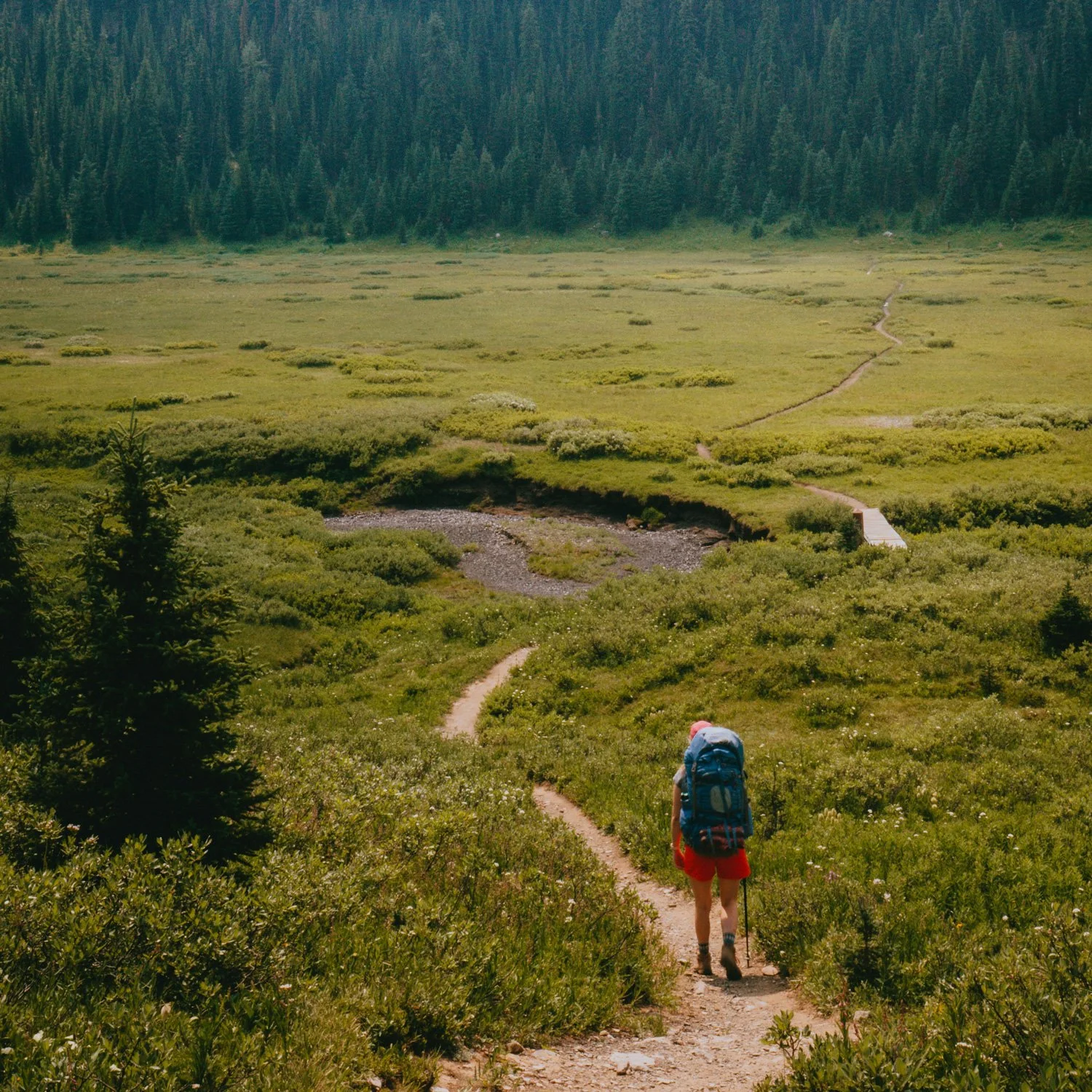 A lone backpacker walks through a mountain valley..