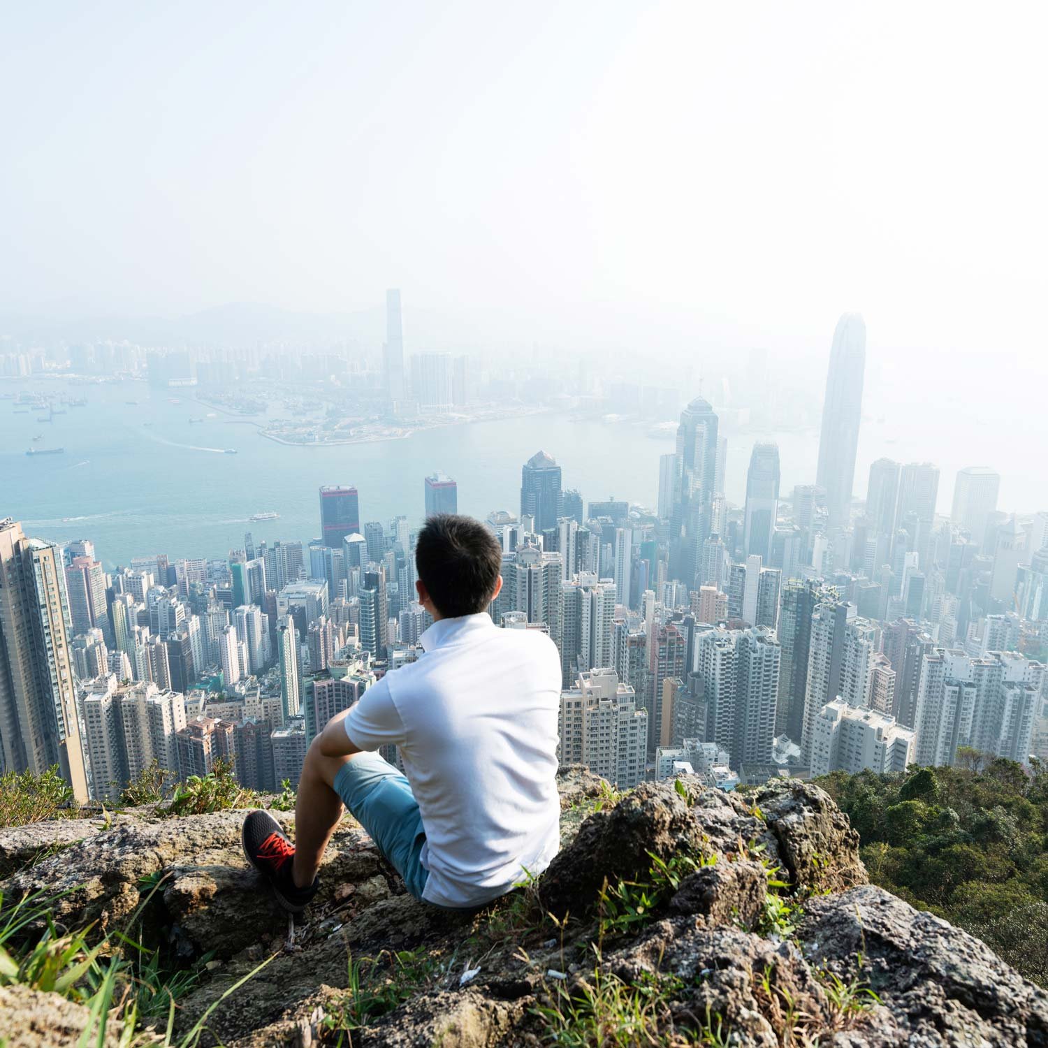 Hikers sits on trail looking down at a large city skyline.