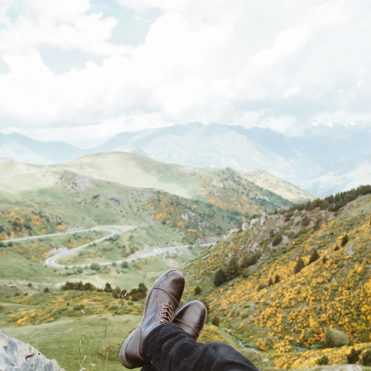 A person rests on a mountain side taking in the view.