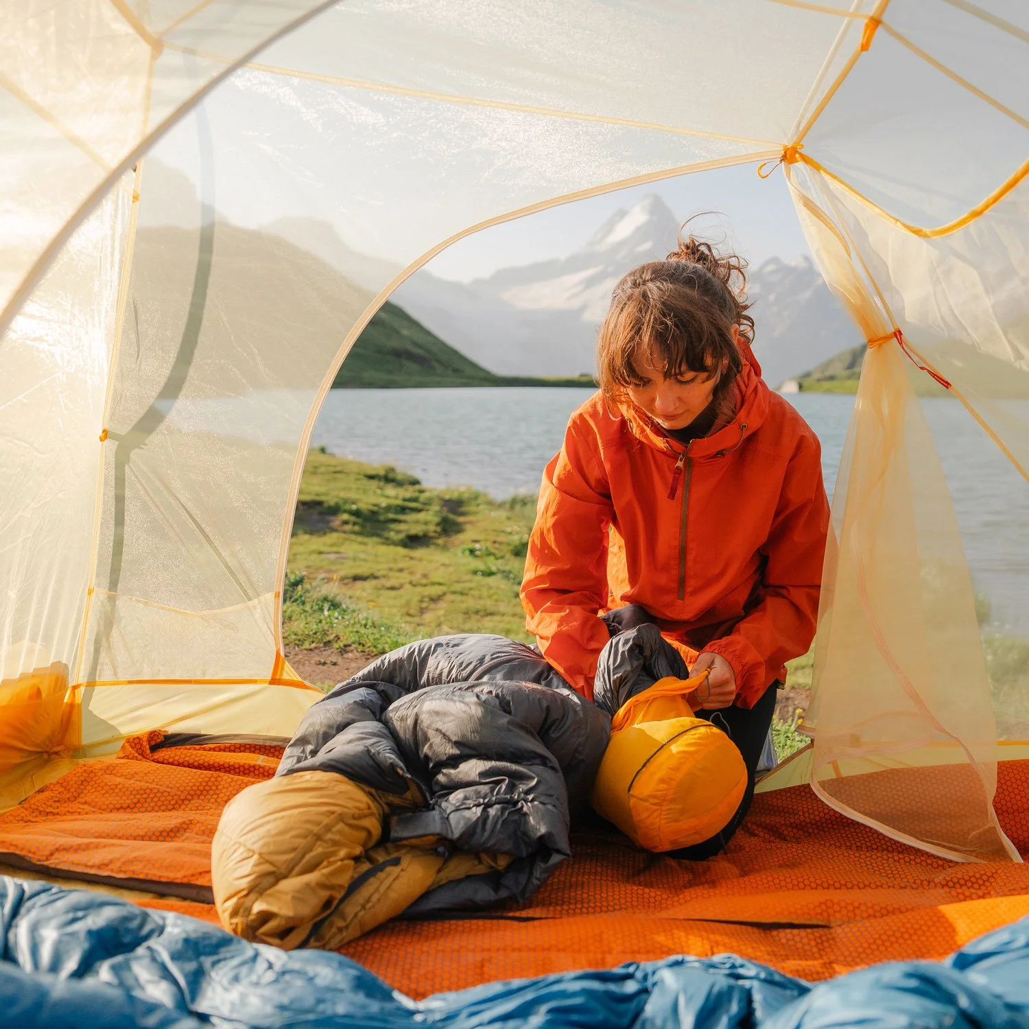 Woman packs her camping gear into a bag.