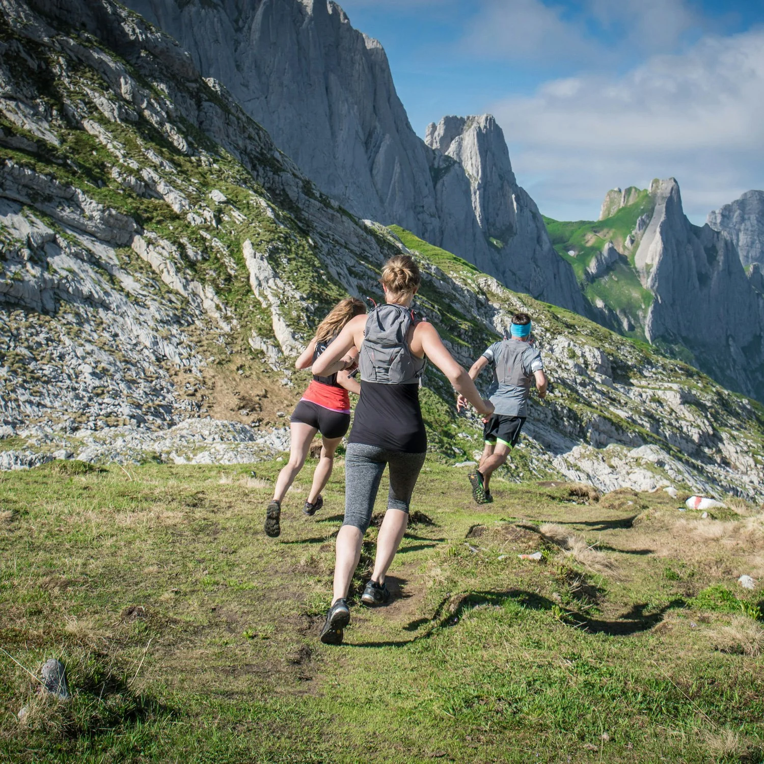 Group of trail runners descend down a mountainside.