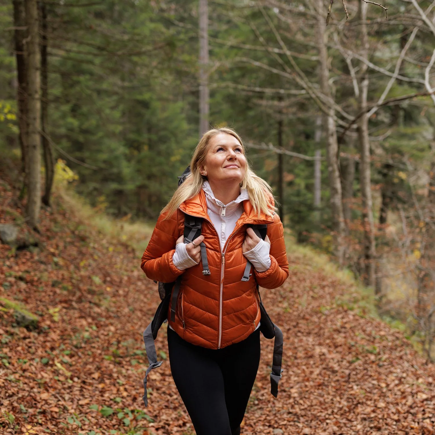 Woman in orange jacket goes for walk outside.