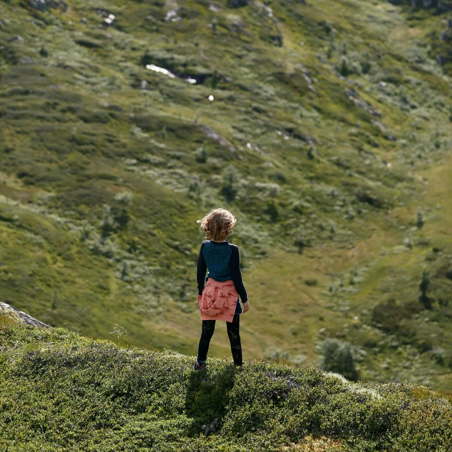Girl stands on the side of hill overlooking the landscape near her campground.