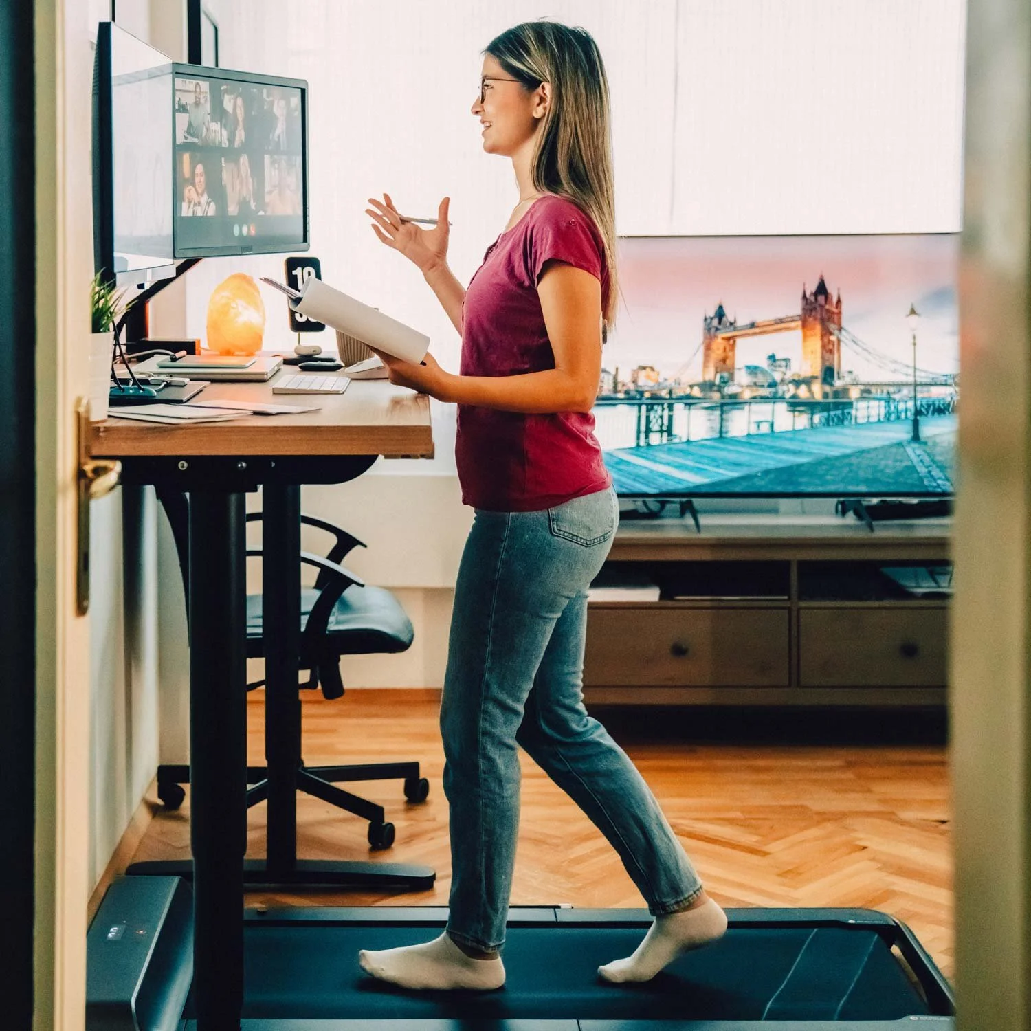 Woman walks on a desk treadmill during a meeting.