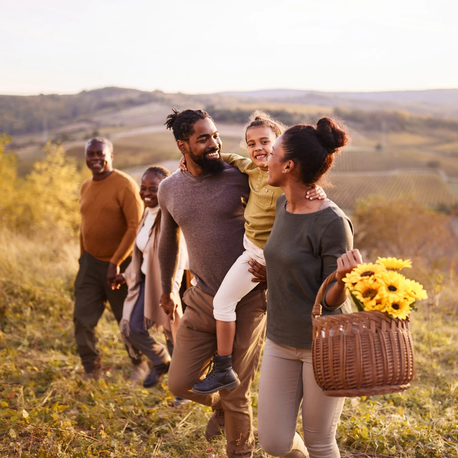 Family walks through a field to setup a picnic.