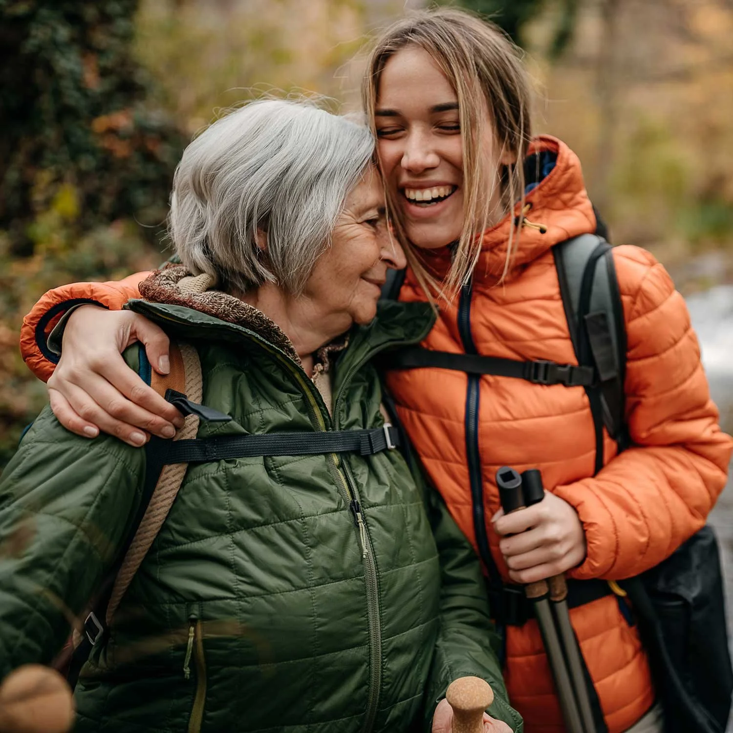 Two women hug during a hike outdoors.