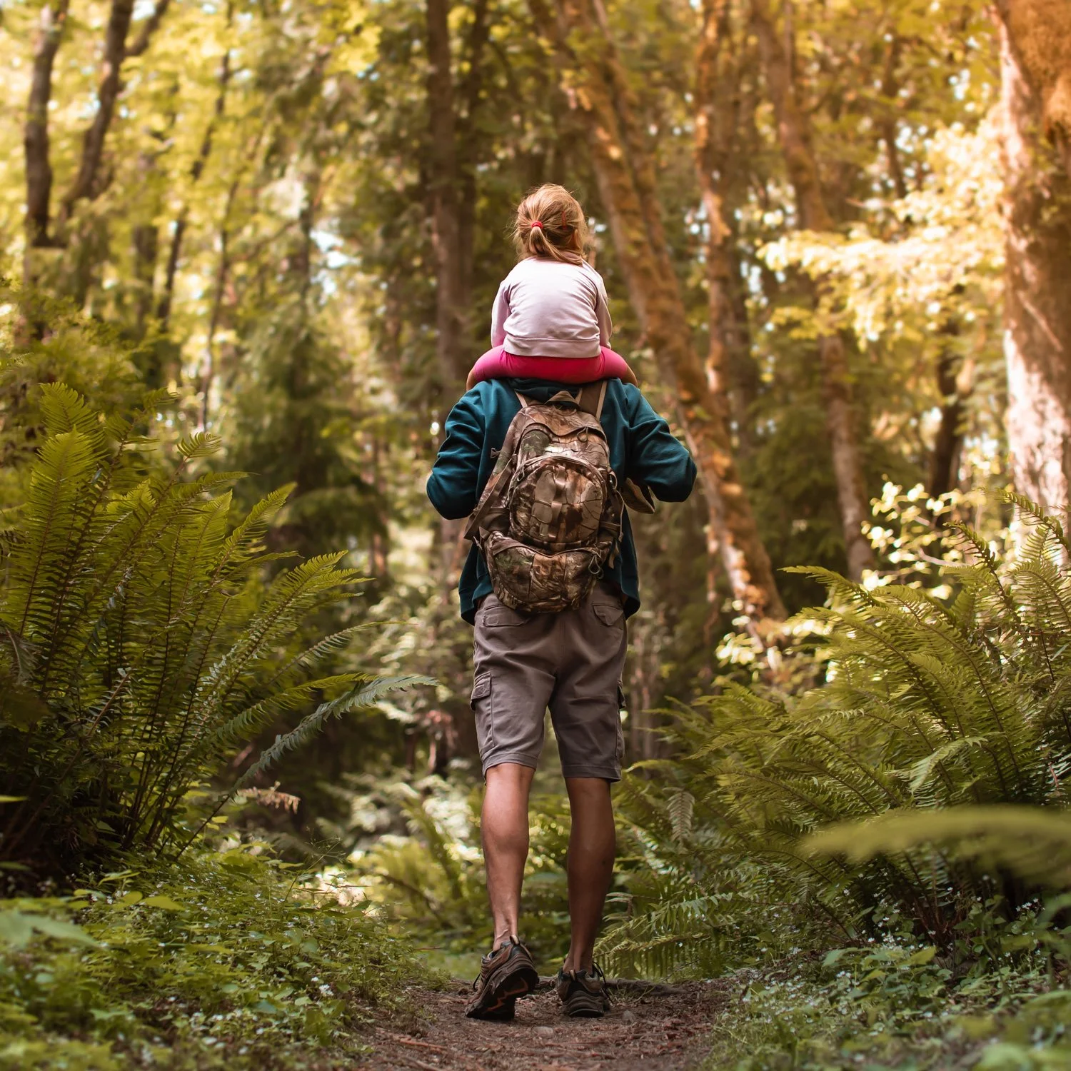 Dad and daughter walk along a hiking trail.
