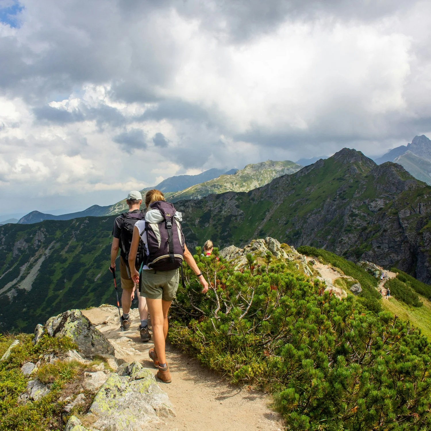 Hikers walk a well worn trail in the mountains.