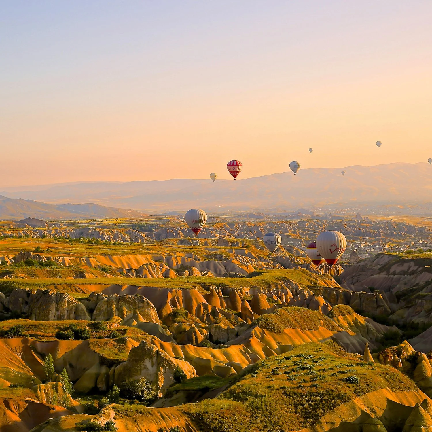 Hot air balloons float over serene landscape.