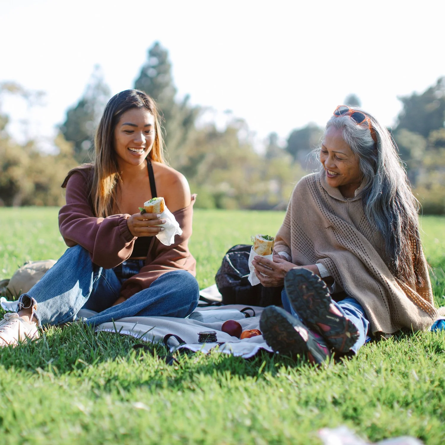 Mother and daughter eat sandwich wraps at a picnic.