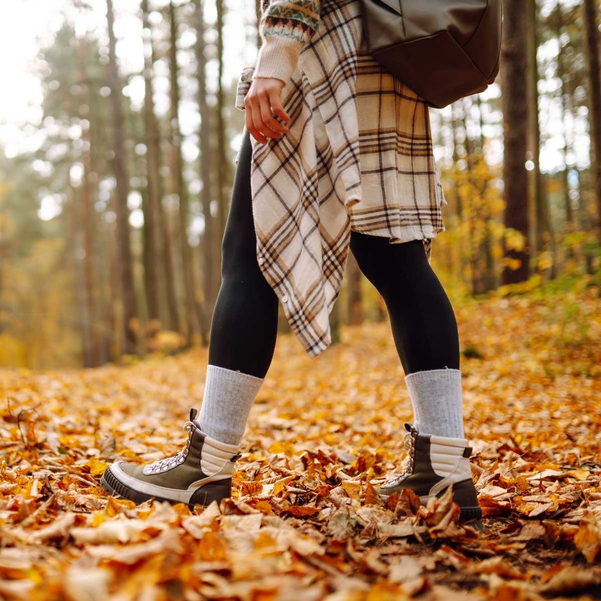 Hiker walks through autumn leaves on an outdoor adventure.