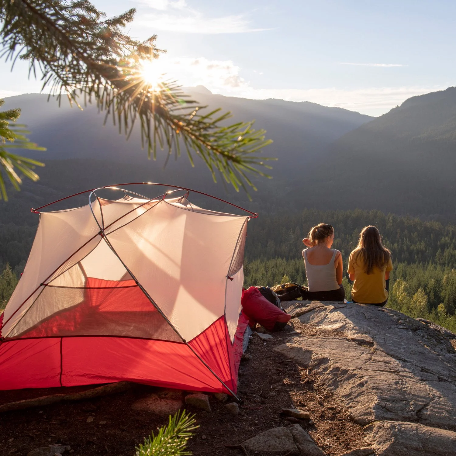 Two people sit near their tent and look at the view.