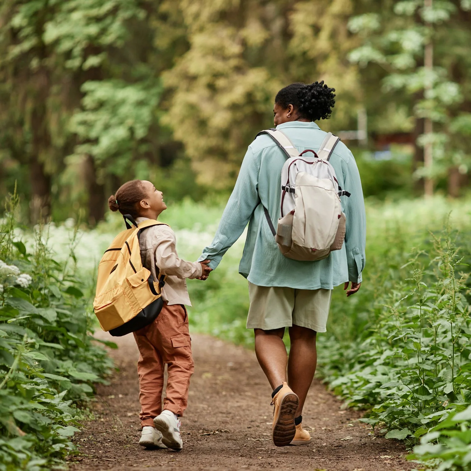 Mother and daughter smiling on a hiking trail.