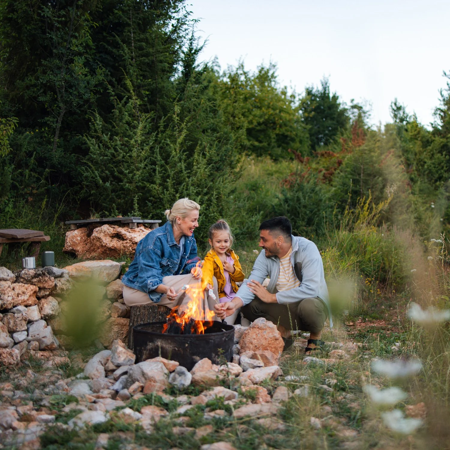 Family roasts marshmellows over a fire while camping.
