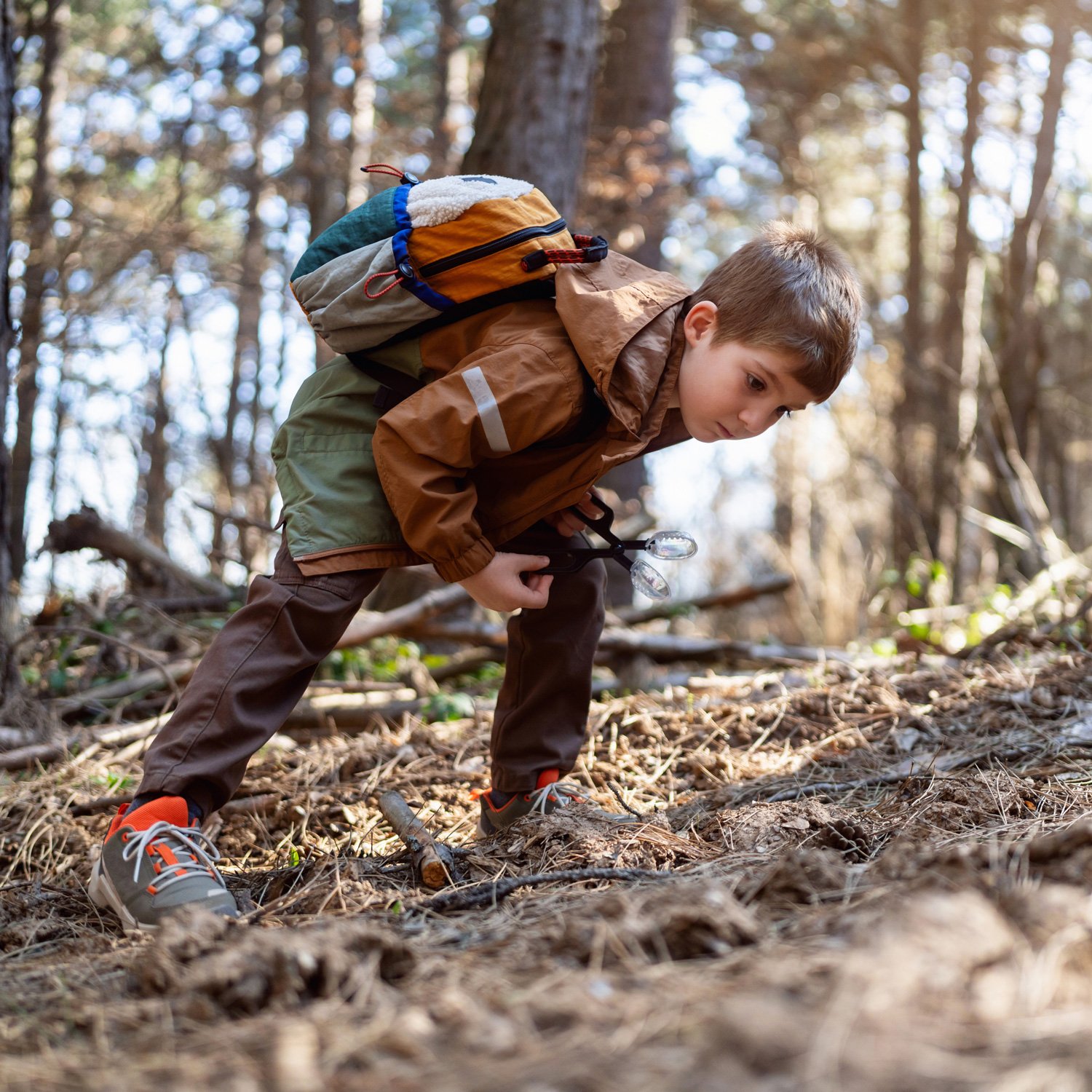 A boy examines sticks and leaves.