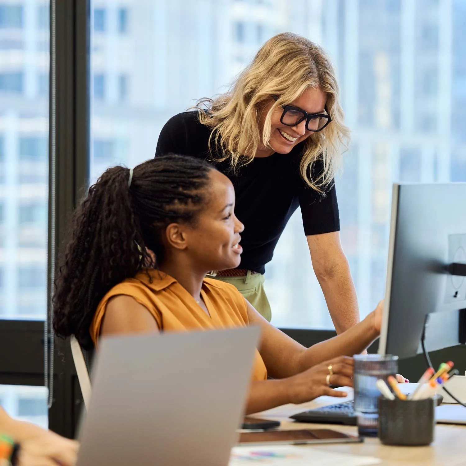 Two employees talk as they look at a computer monitor.