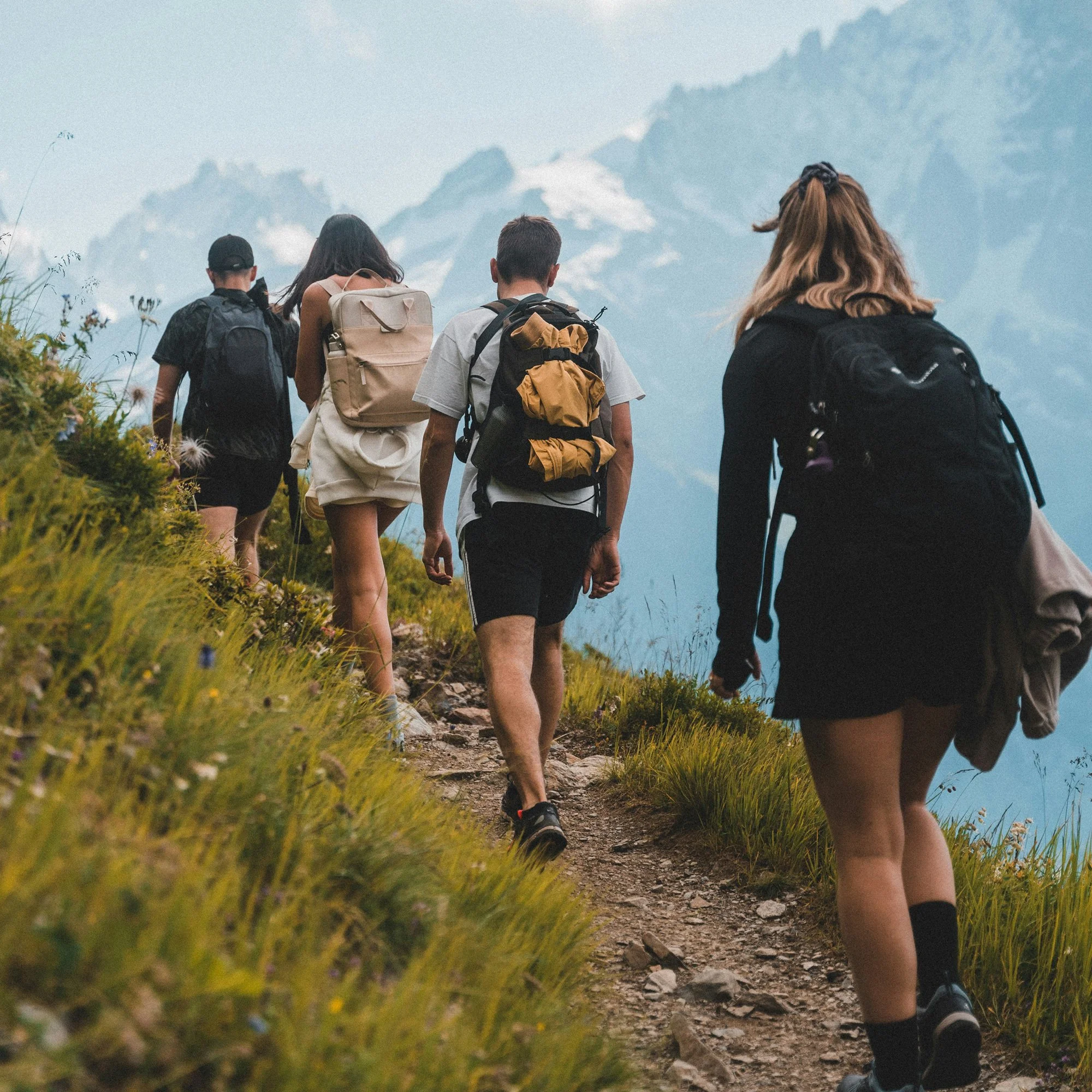 Group of young people hike up a mountain trail.