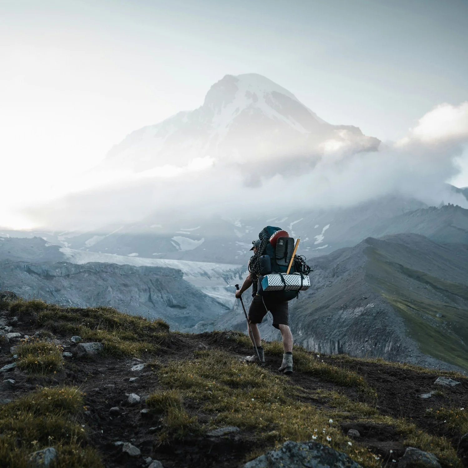 Backpacker hikes up a cloudy mountainside.
