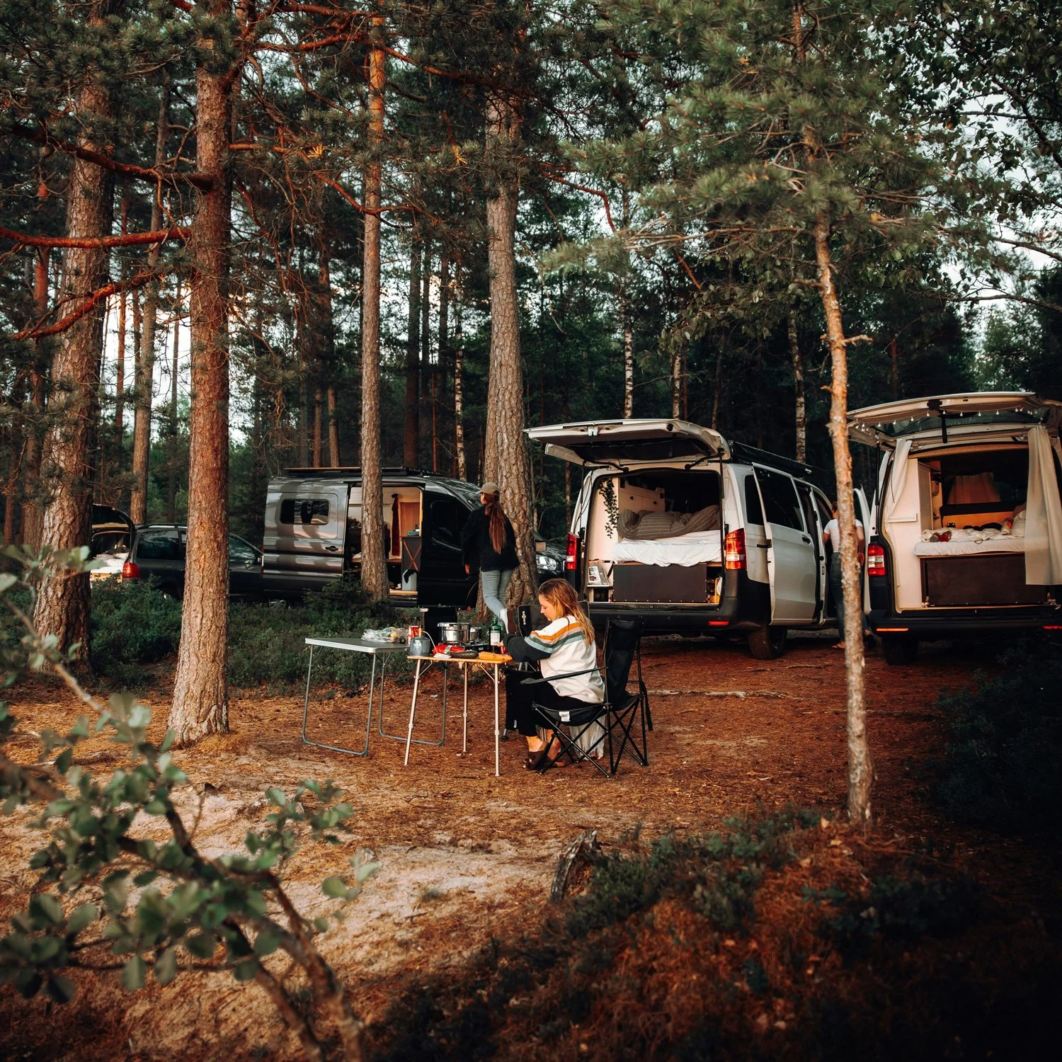 Woman prepares meal at a car camping event.