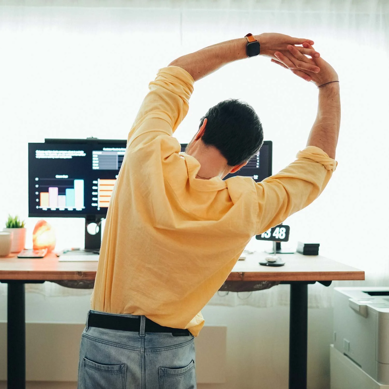 Man stretches at his desk.