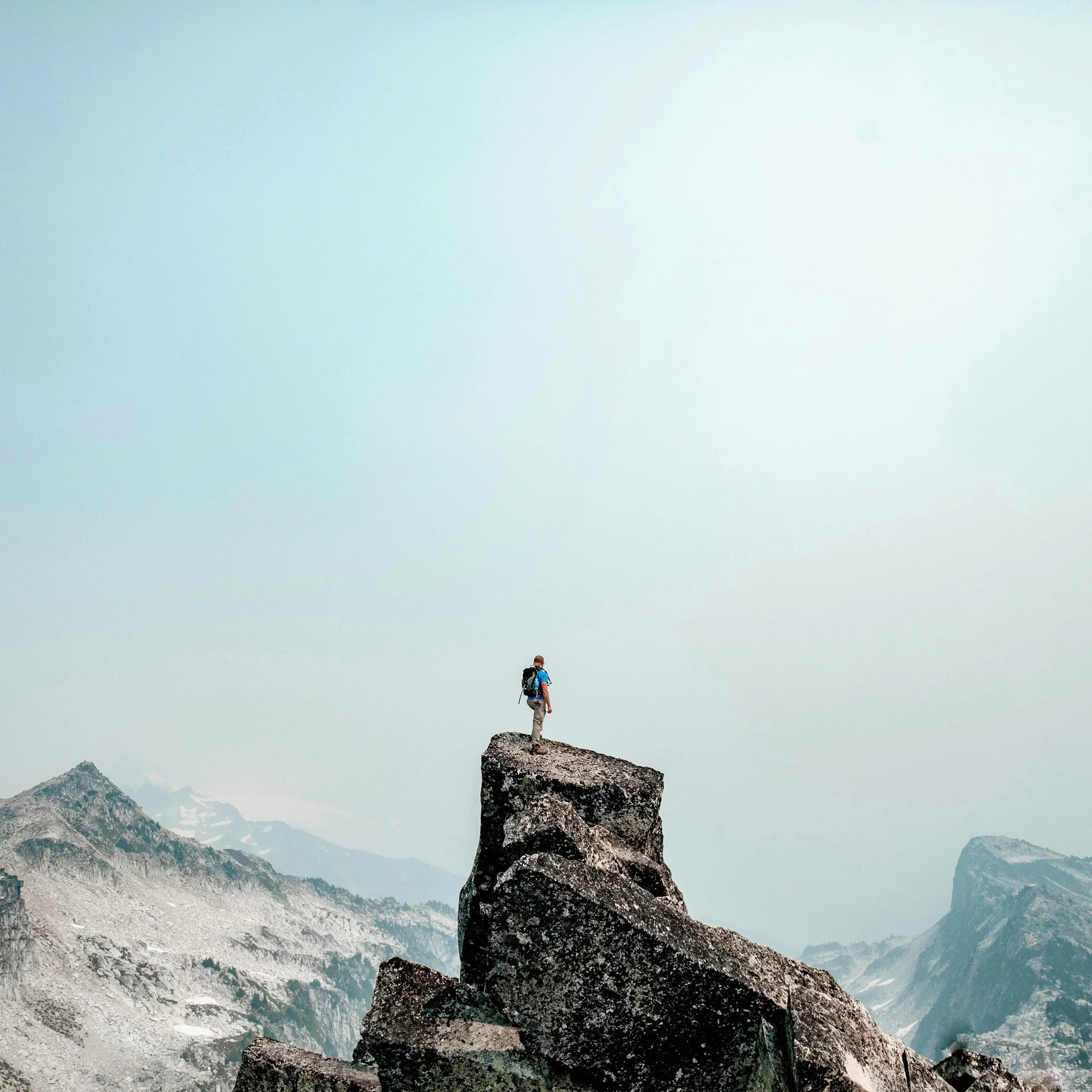 Man stand atop a large rock outcropping.