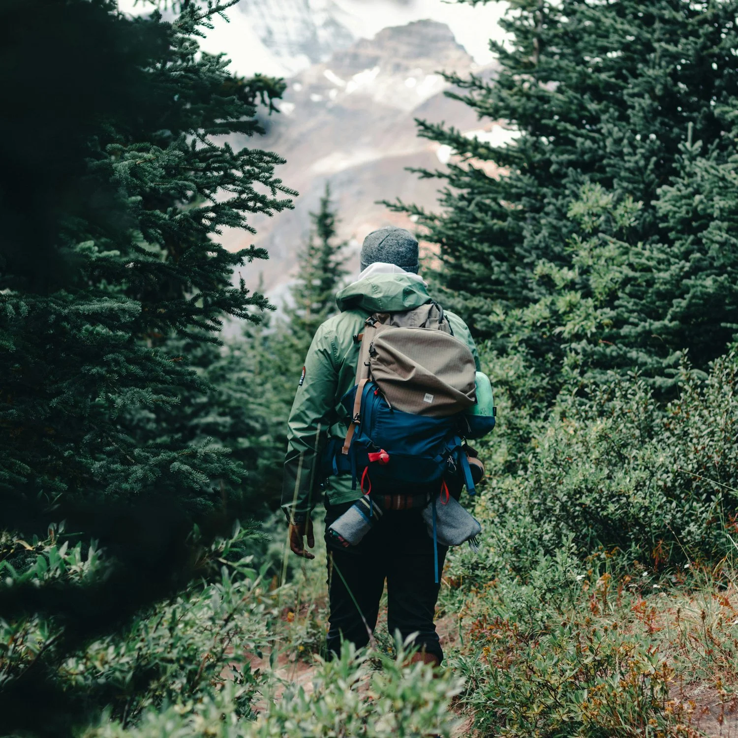 Person with lots of backpacking gear stands in the woods.