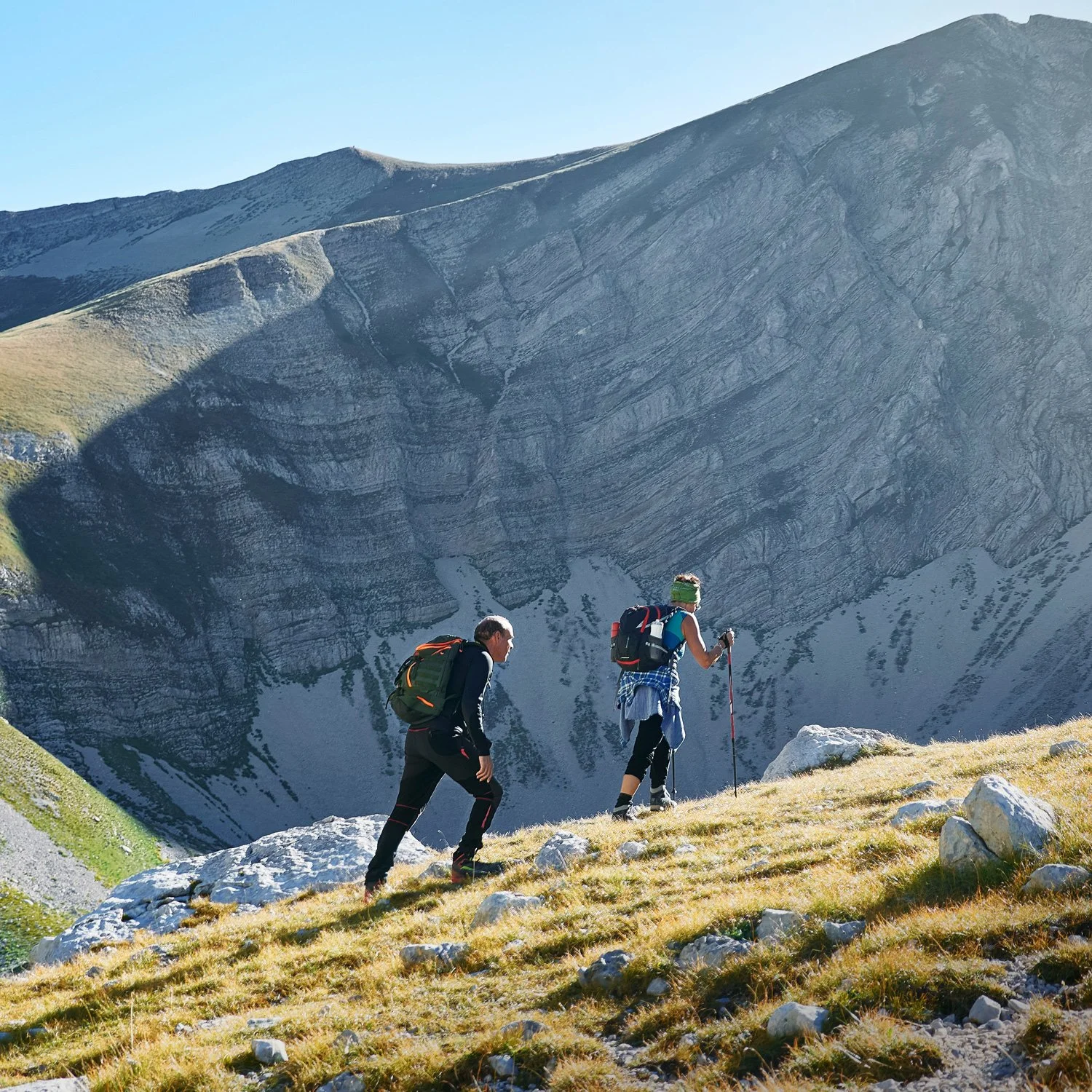A man and woman hike up steep mountain trail.