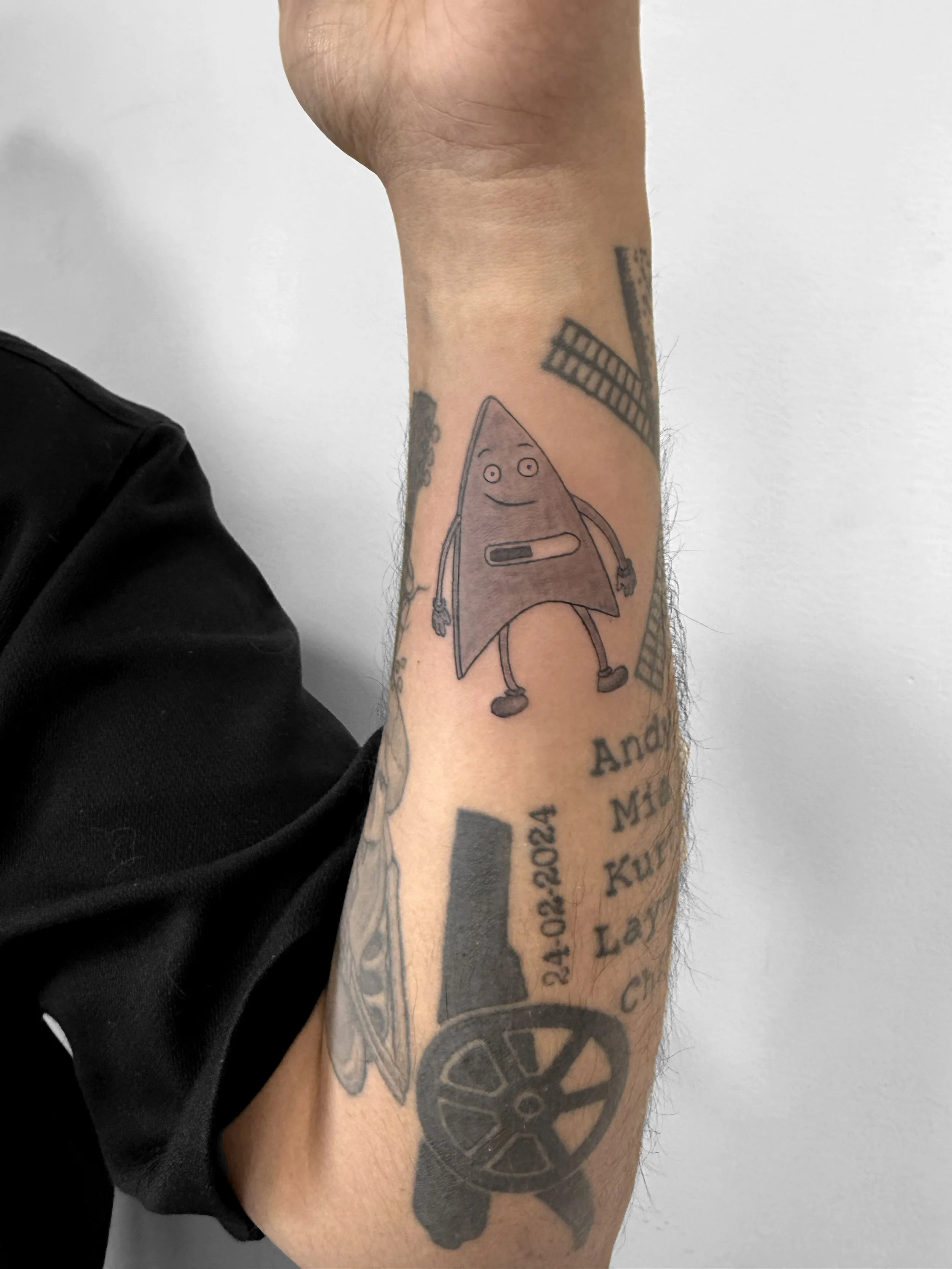 Tattoo on person's arm of a cartoon arrow character with a smiling face and arms and legs.