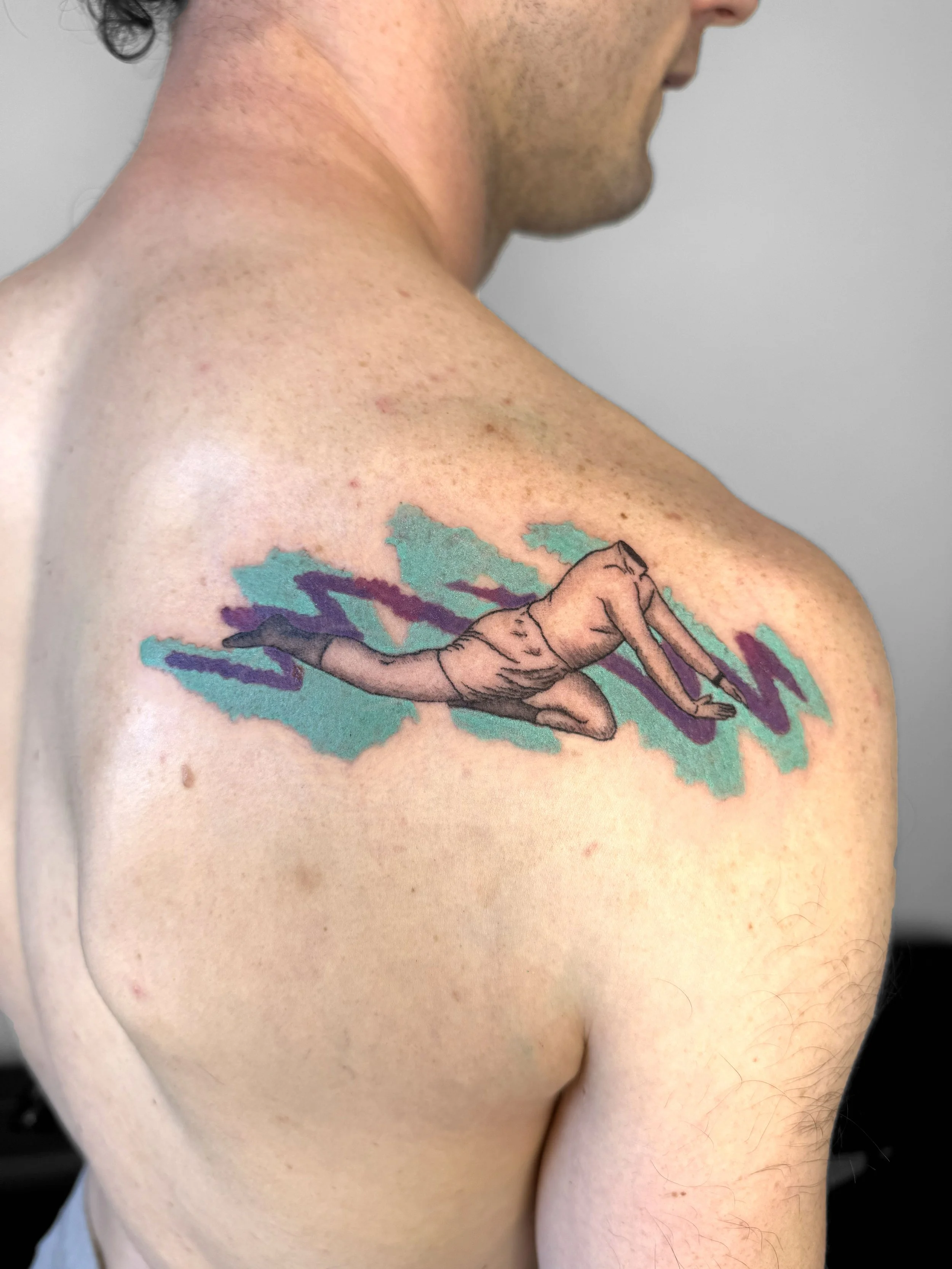 A tattoo of a person in a yoga pose on a person’s shoulder, with colorful abstract background elements.