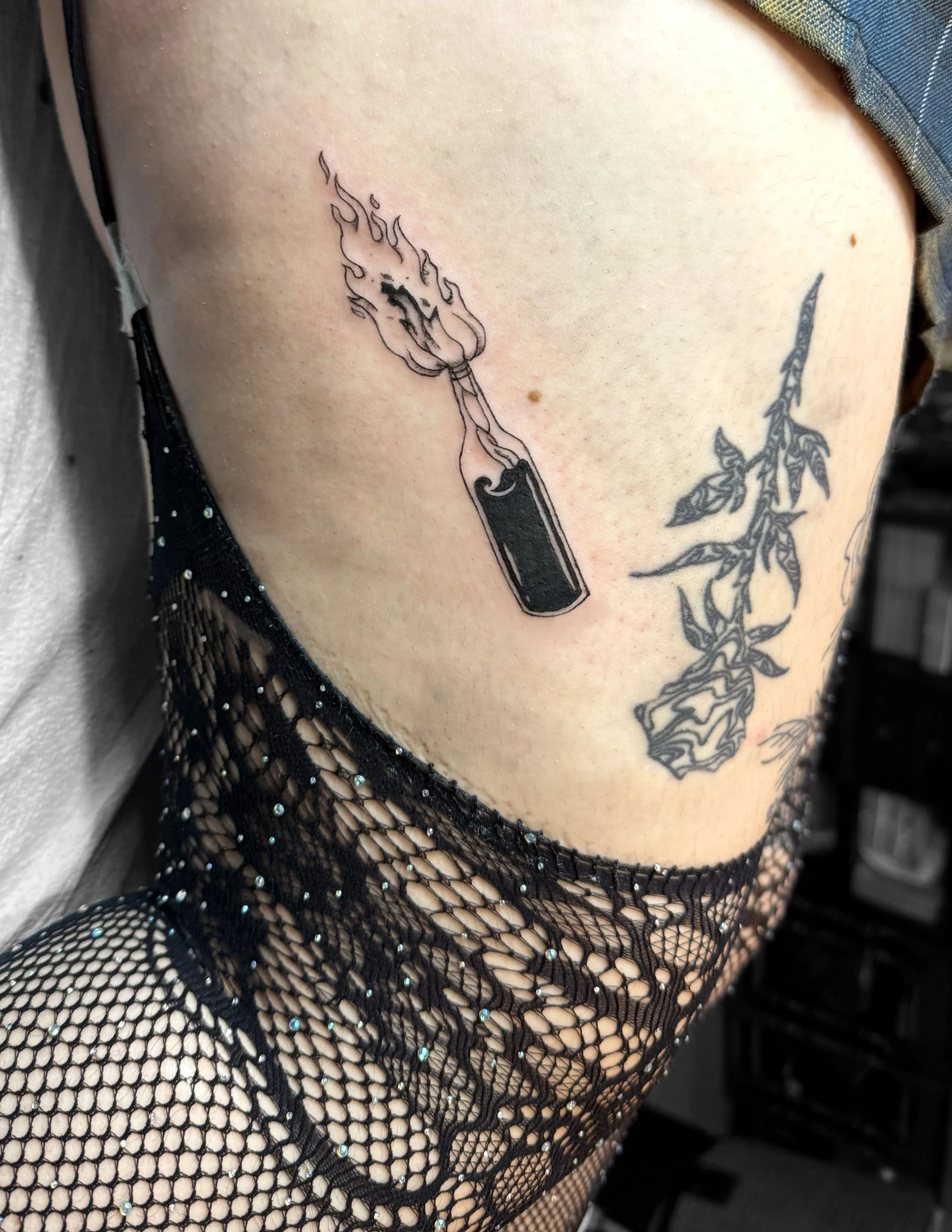 Tattoo of a lit matchstick on a person's upper arm.