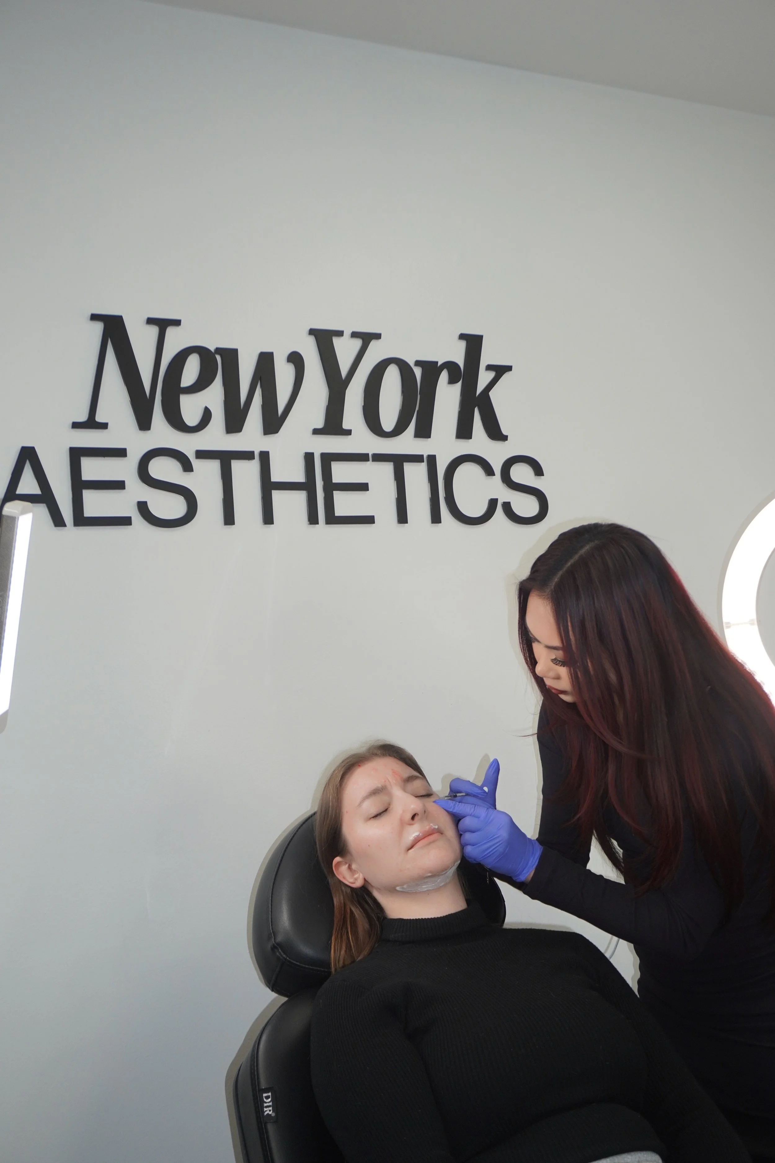 A woman receiving a cosmetic procedure from a professional at New York Aesthetics clinic.