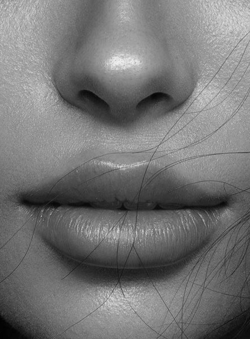 Close-up black and white photo of a person's nose and lips, with some fine hair visible on the face.