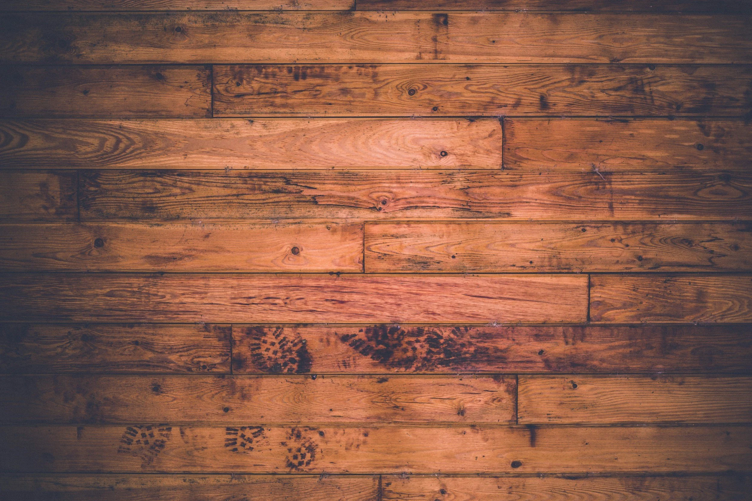 Wooden floor with a warm, brown finish showing knots, grains, and some the streaks darker than others.