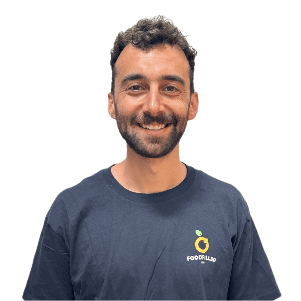 A smiling man with dark hair and beard, wearing a navy t-shirt with a FoodFilled logo.