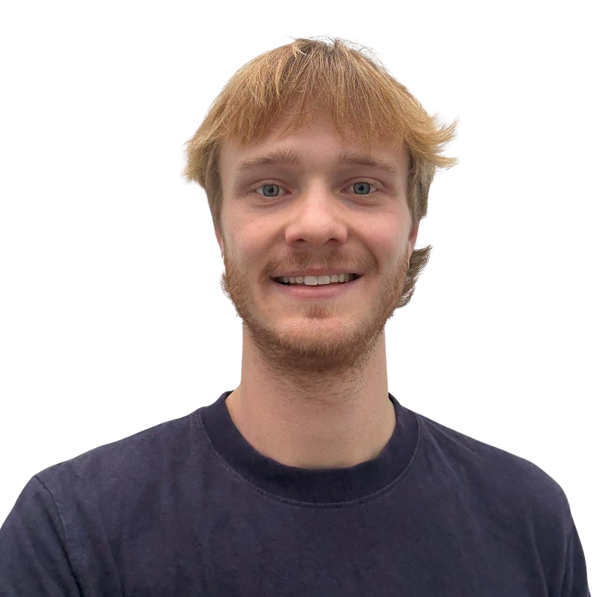 A young man with blonde hair, blue eyes, and a light beard smiling at the camera, wearing a dark t-shirt.