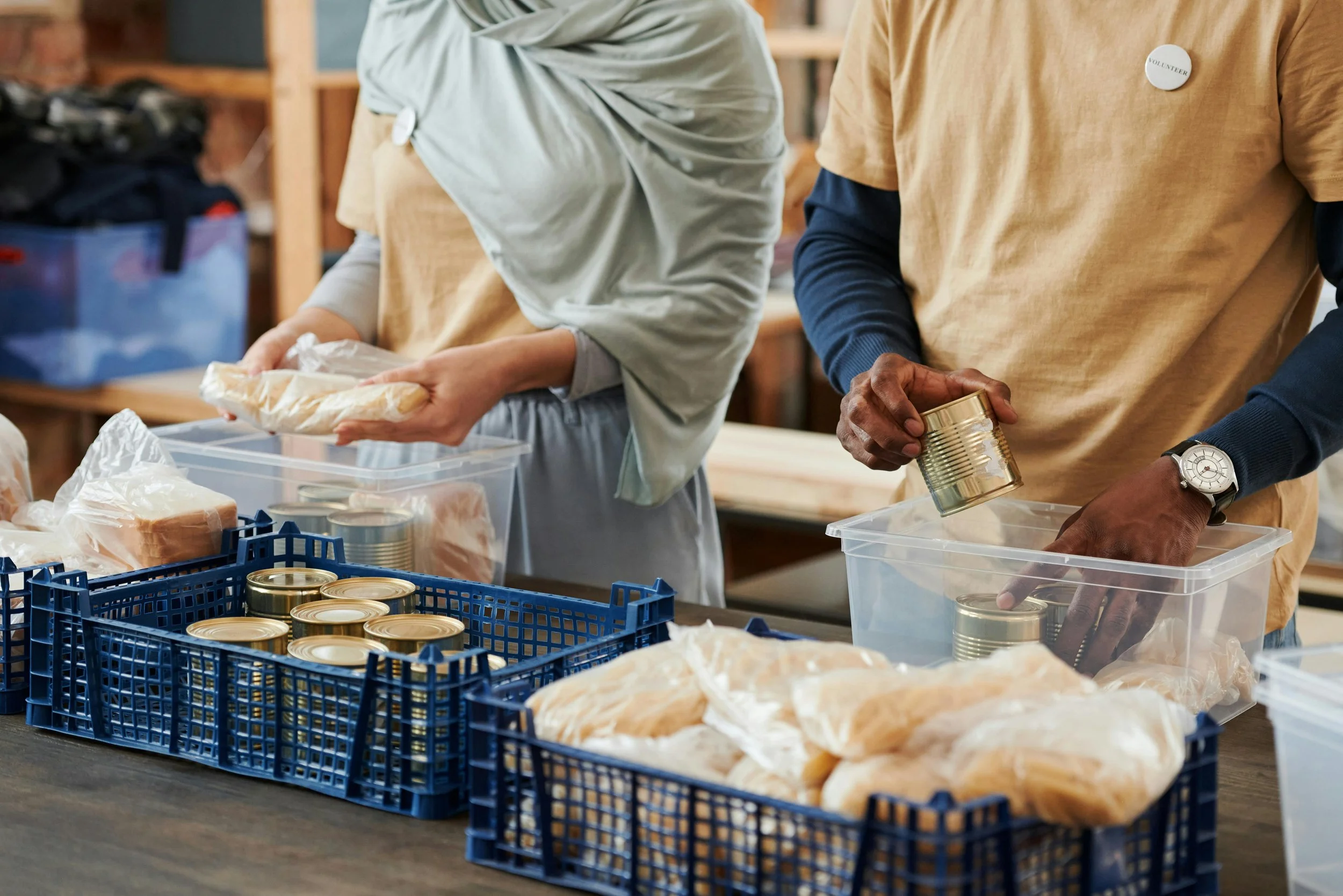 People packing canned goods and bread into plastic containers at a volunteer event.