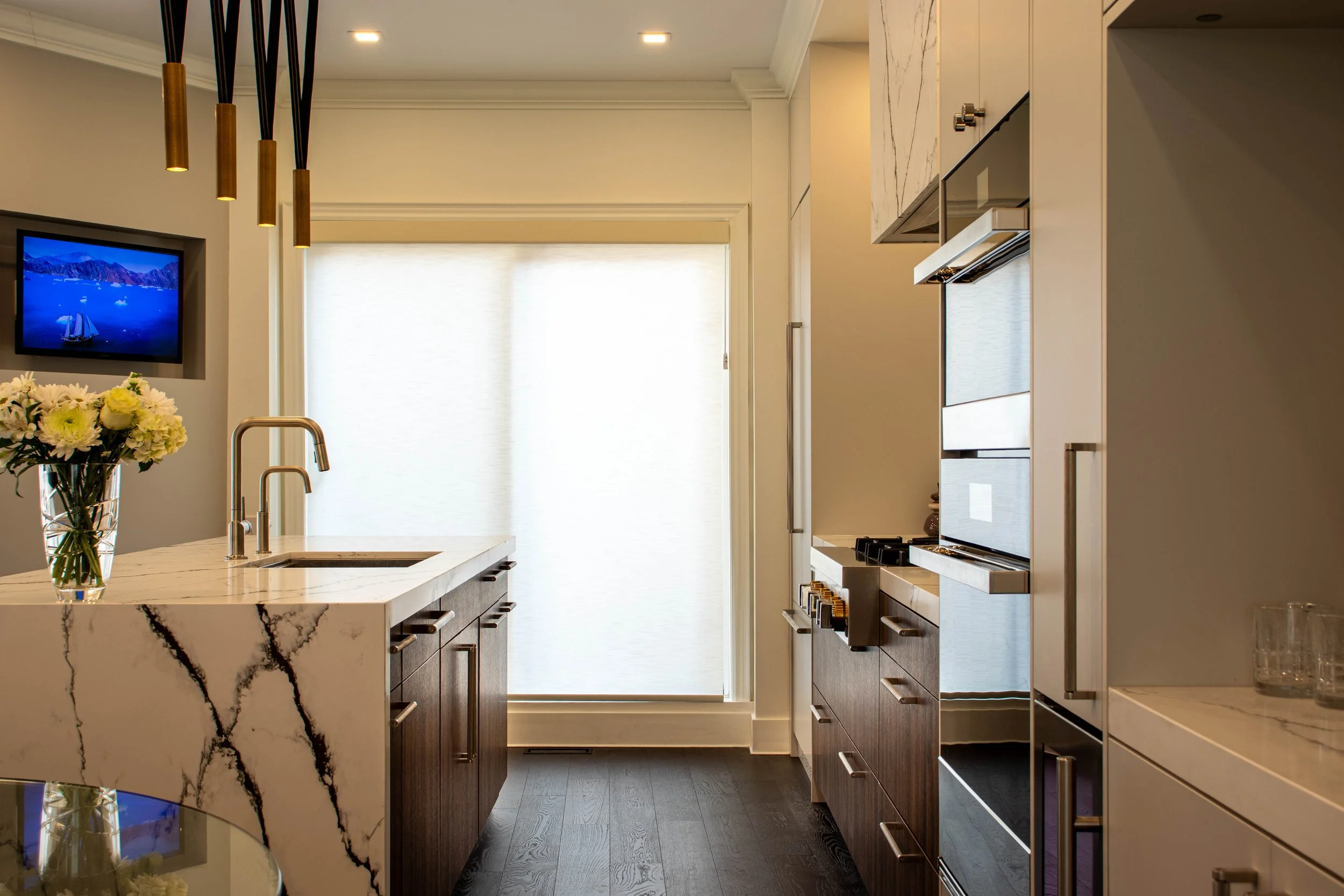 Minimalist modern kitchen with marble surfaces, custom wood cabinetry, and designer lighting