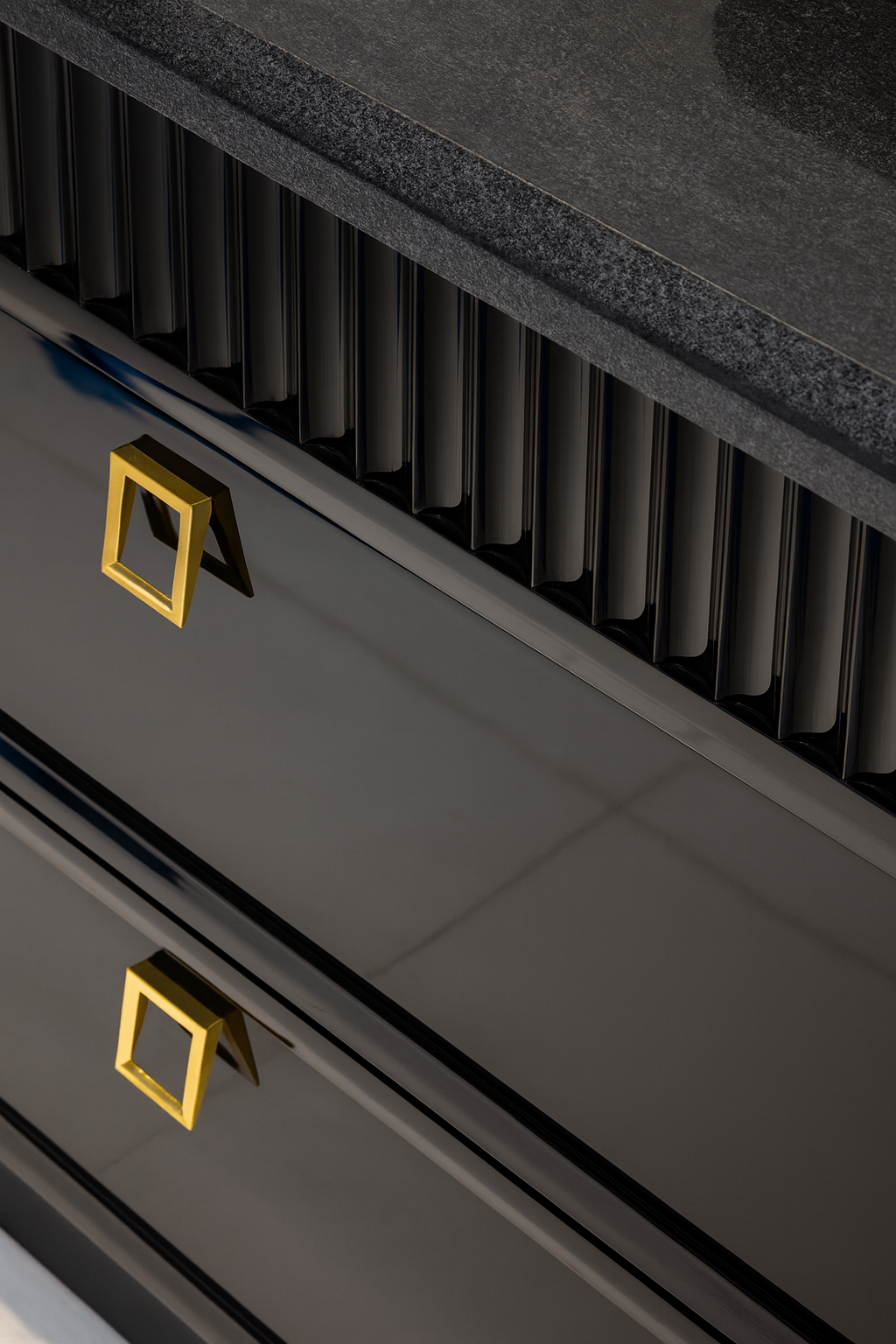 Close-up of custom kitchen cabinetry featuring matte black finish, fluted detailing, and gold hardware accents.