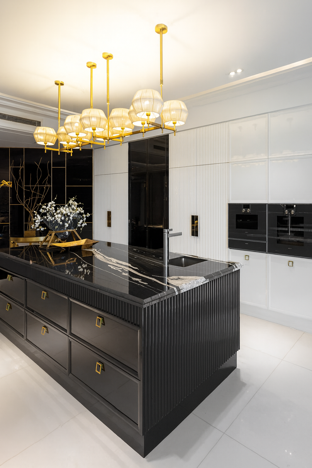 Luxury kitchen design featuring a black custom island, gold pendant lighting, and sleek cabinetry, thoughtfully designed for everyday family use.