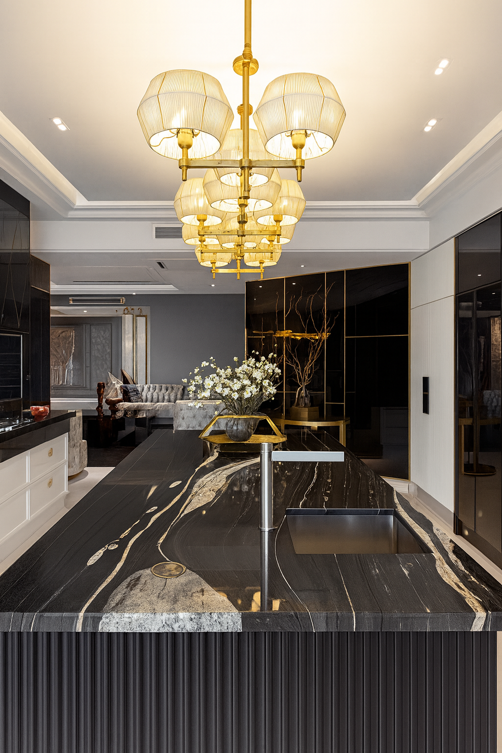 Luxury kitchen island with black stone countertop, integrated sink, statement chandelier, and custom cabinetry designed for a modern family home.