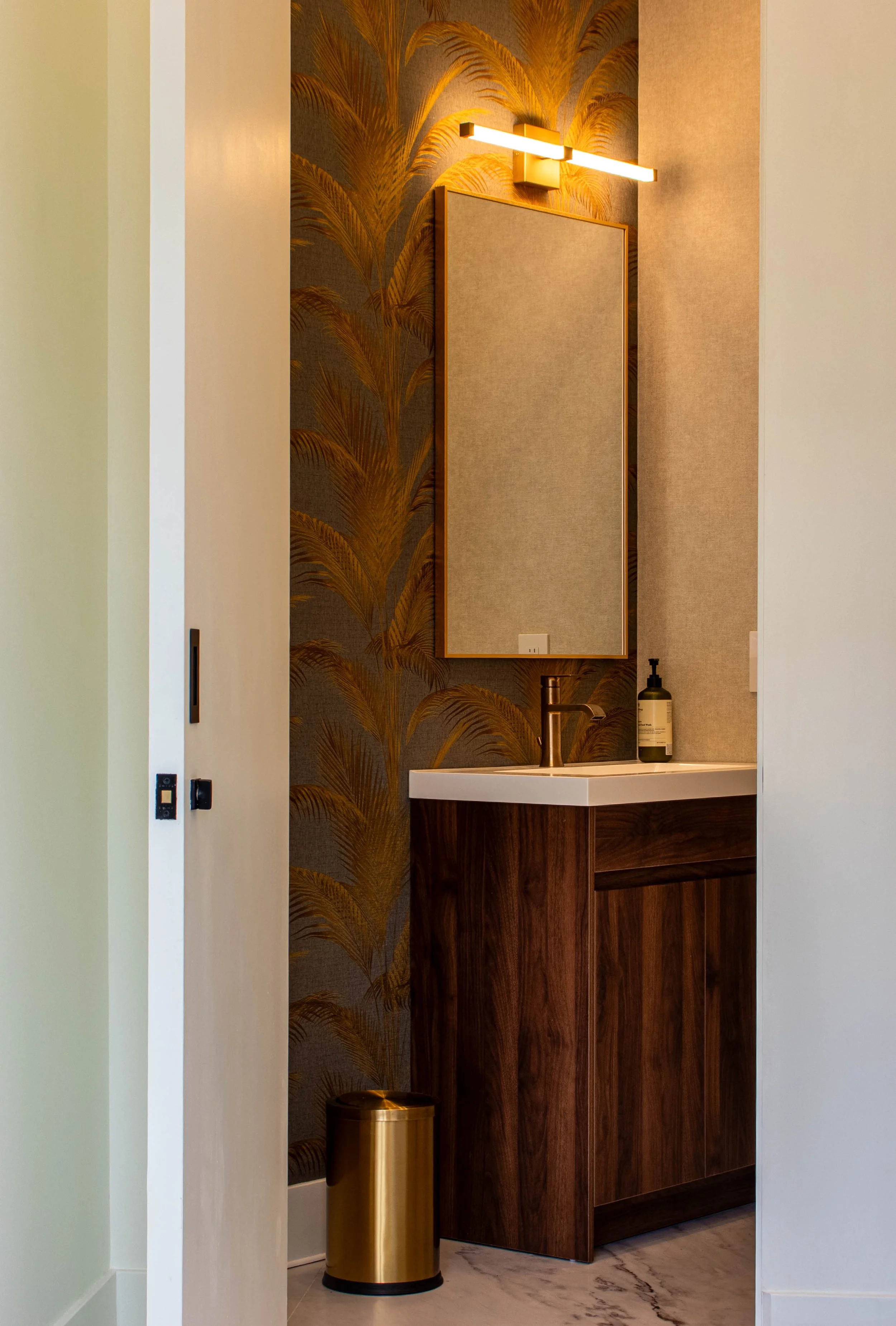 Luxury powder room interior design in Toronto featuring custom wood vanity, statement wallpaper, and modern wall-mounted lighting