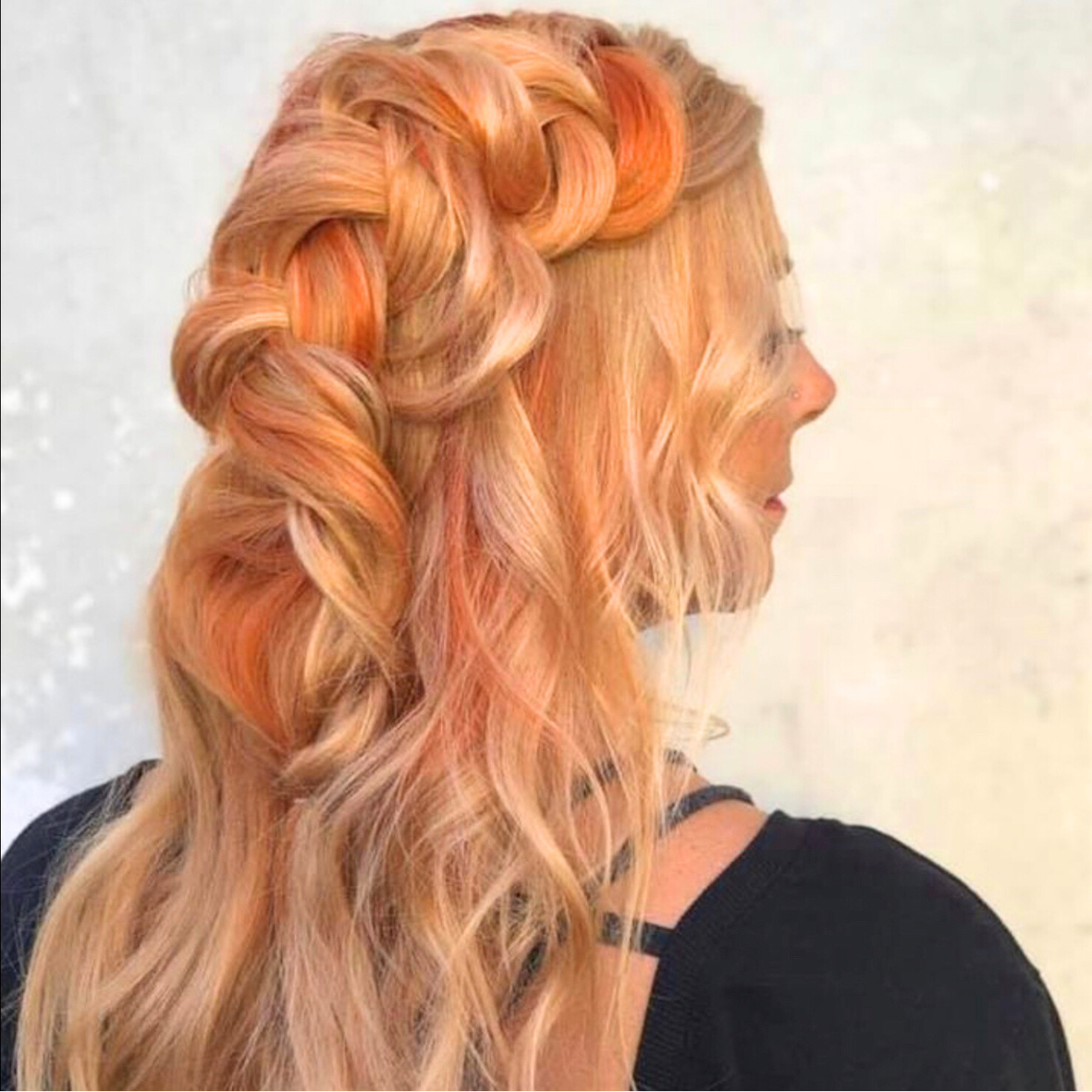 Side view of a woman with long, wavy, and curly blonde hair with warm highlights, styled in loose, voluminous waves.