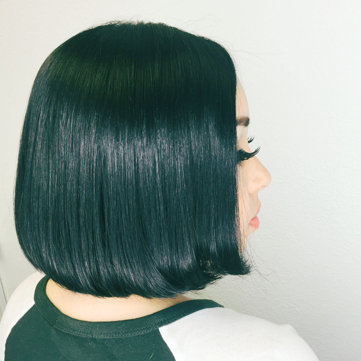 Side view of a woman with sleek, shiny, black bob haircut.