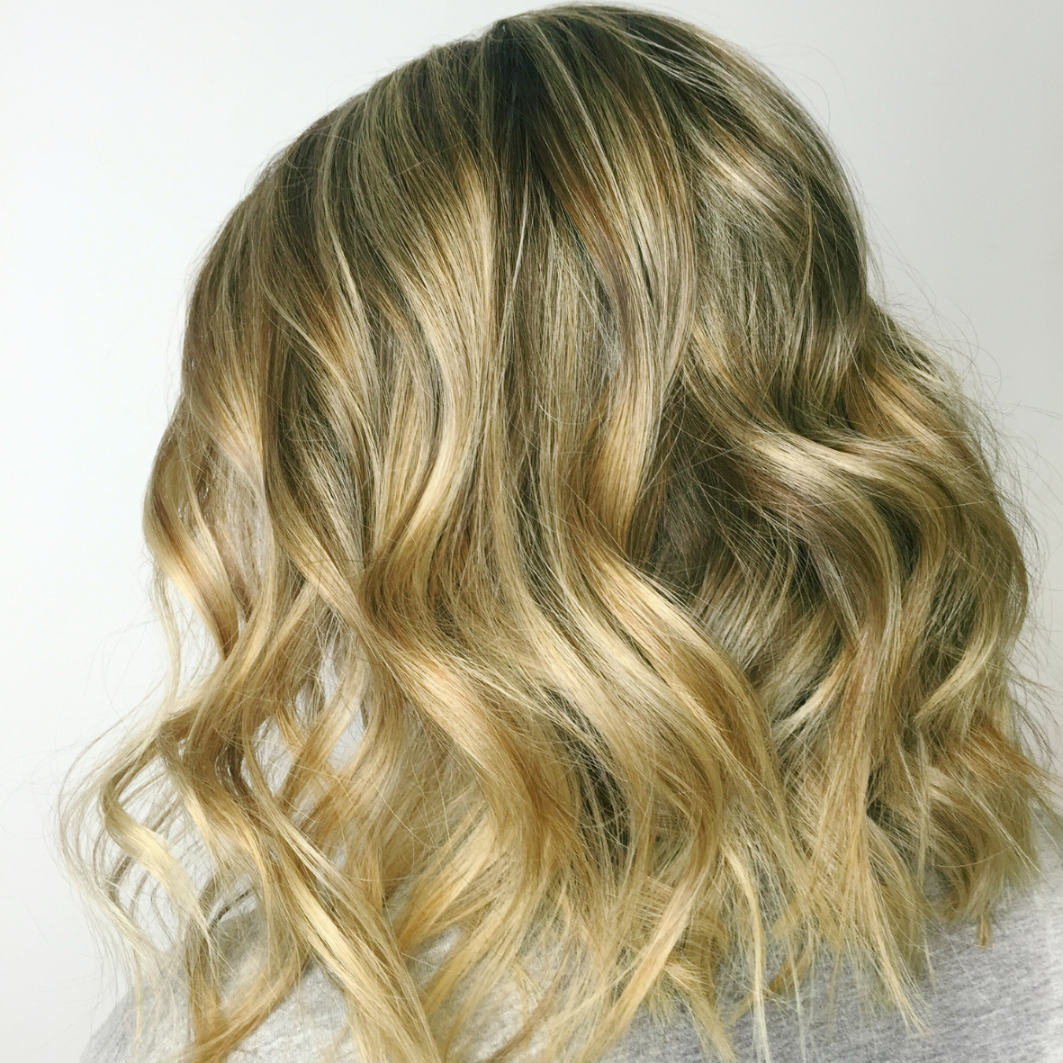 Close-up of shoulder-length blonde hair styled in loose curls.